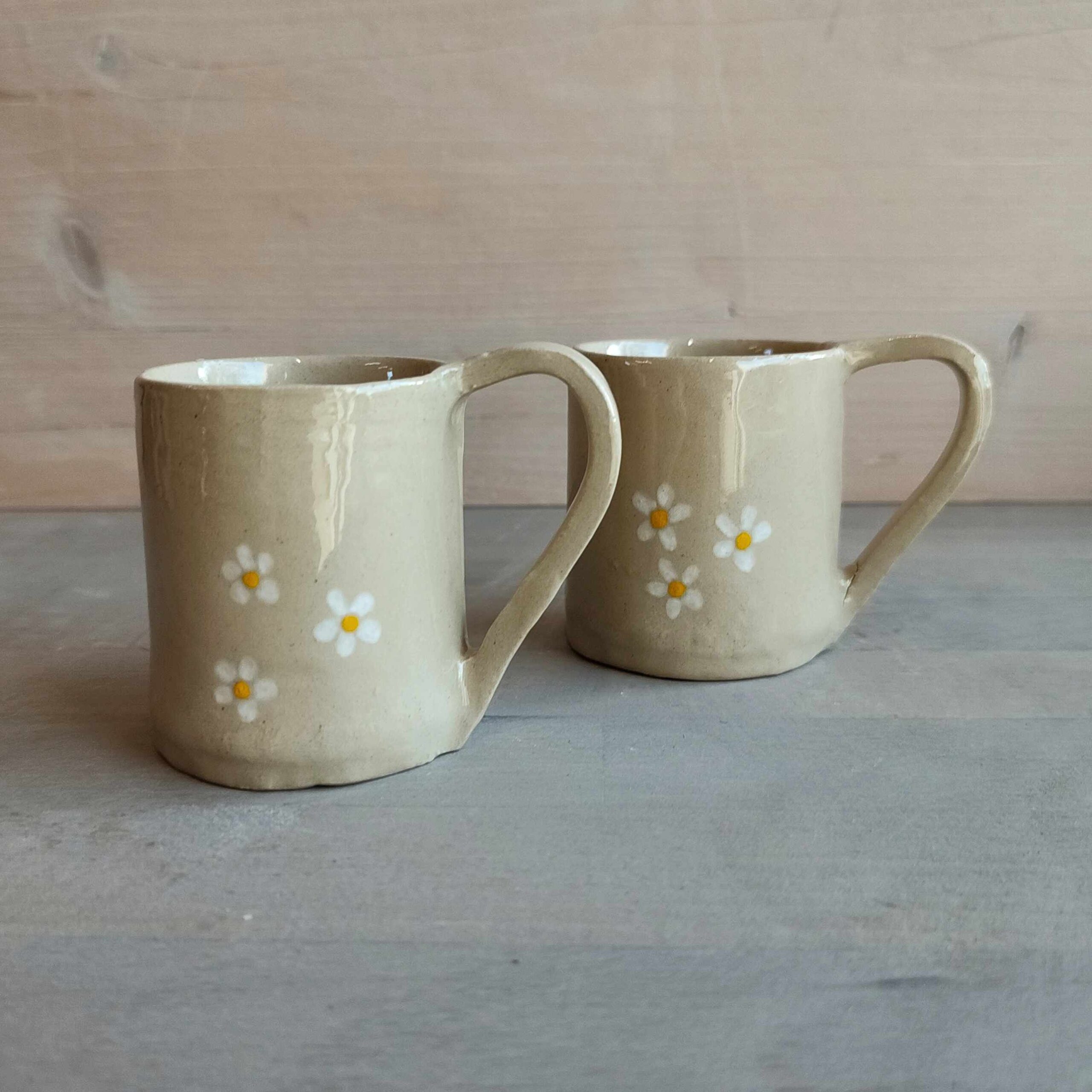 Photographie de deux tasses à expresso beige avec deux dessins de marguerite