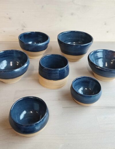 Photograph of seven objects—one cup and six blue bowls