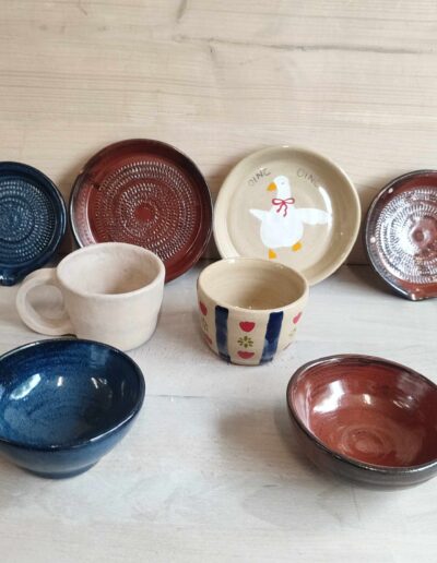 Photograph of 8 pieces of tableware, including 2 garlic graters, two cups, one plate, and two bowls