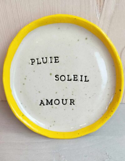 Photographie d'une assiette dans la quelle est marqué "pluie, soleil et amour"