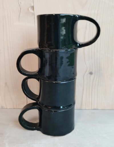 Photographie de quatre tasses noirs empilées